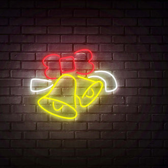 Bells with Red Ribbon NEON LED Sign glowing on a brick wall, perfect for festive decor and custom sign inquiries.