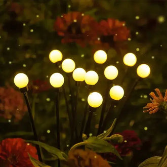LED Firefly Lights - Solar Powered - 10 LEDs illuminating a garden with yellow lights among flowers at night.