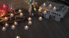 Warm white LED tealight candles flickering on wooden table with decorations and books.